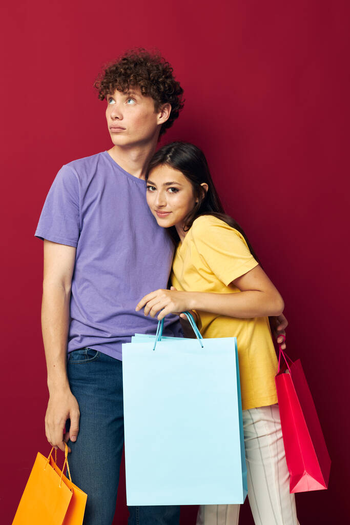 young boy and girl colorful bags shopping fun red background unaltered - Photo, Image