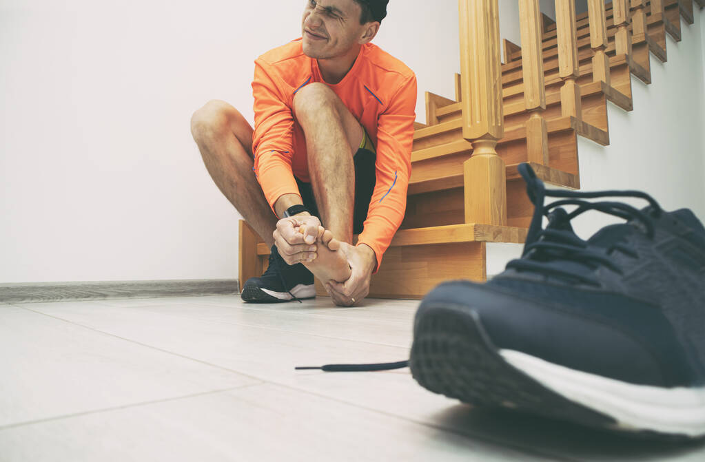 Der Läufer bereitet sich auf das Laufen vor und verrät, dass sein Fuß schmerzt - Foto, Bild