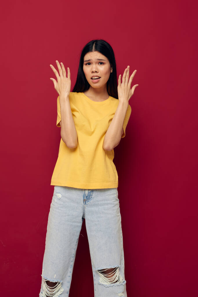 Portrait asiatique belle jeune femme gestes avec ses mains dans un t-shirt jaune casual porter modèle studio inchangé - Photo, image