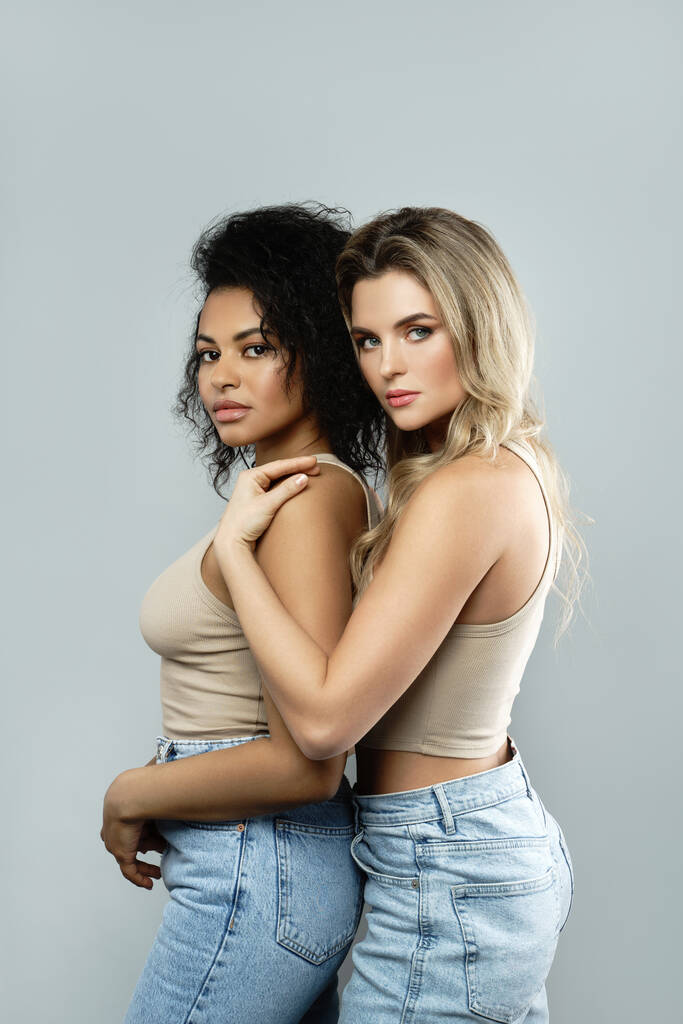 Portrait of Caucasian and African American women on gray background. Concepts of beauty and fashion, interracial friendship or lesbian relationship. - Photo, Image