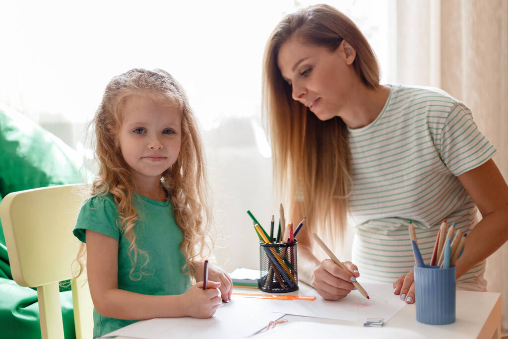 Portrét dcery a matky kreslí spolu trávit volný čas hrát zábavu doma. Kavkazský blondýnka těhotná matka pomáhá dítě předškolní dívka dcera dělá domácí úkol. - Fotografie, Obrázek