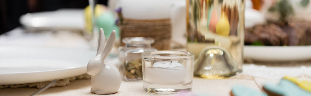 селективный фокус декоративного кролика и свечи на столе подается на пасхальный ужин, баннер - Фото, изображение