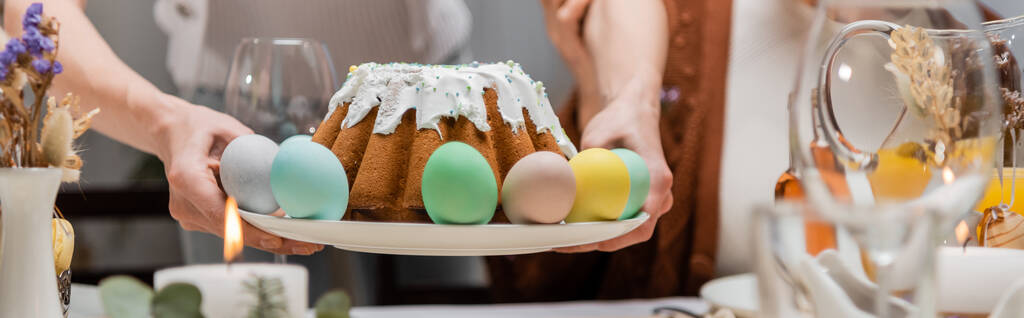 rajattu näkymä nainen tilalla levy maukas pääsiäinen kakku ja maalattu munat, banneri - Valokuva, kuva