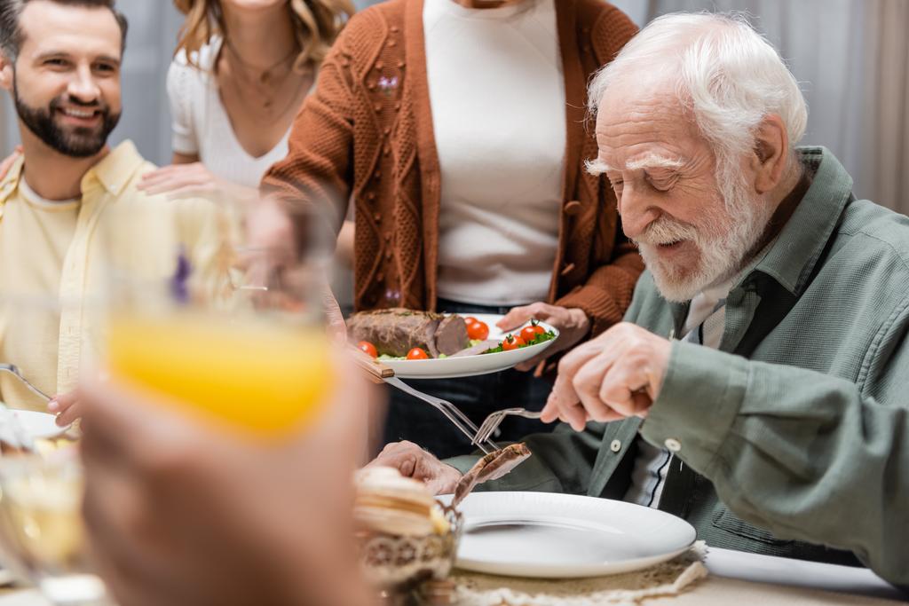donna anziana che serve carne fritta durante la cena di Pasqua con la famiglia - Foto, immagini