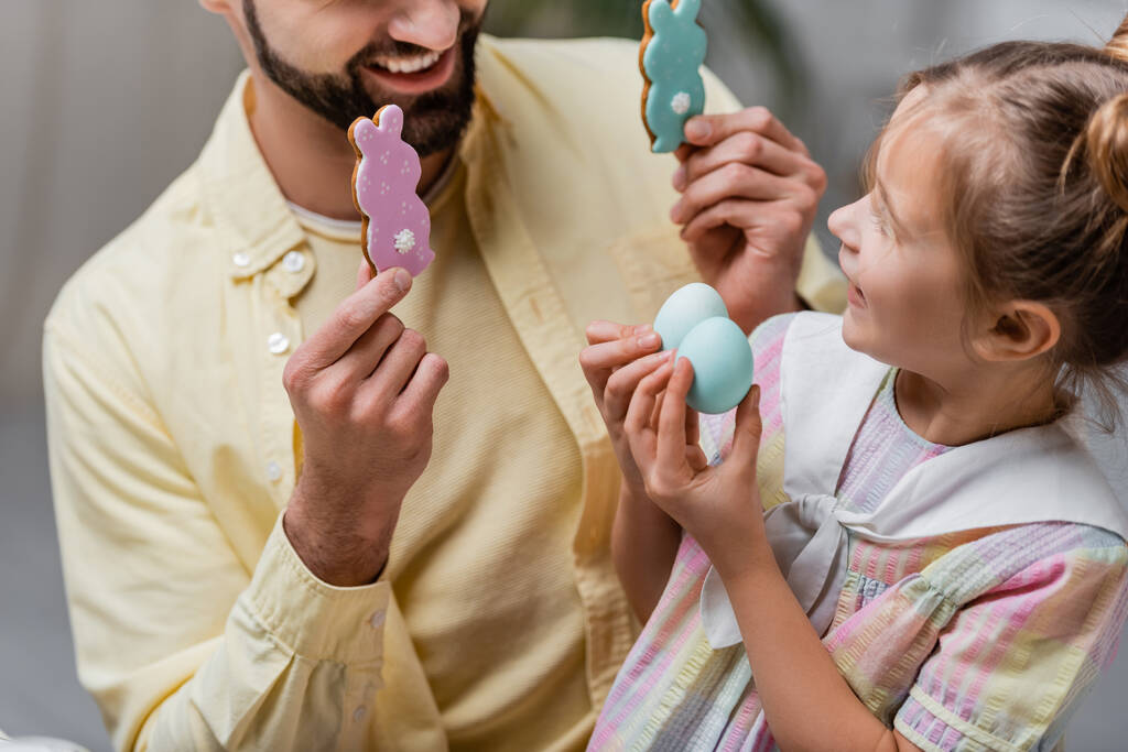 веселий чоловік з дочкою тримає великодні яйця і традиційне печиво
 - Фото, зображення