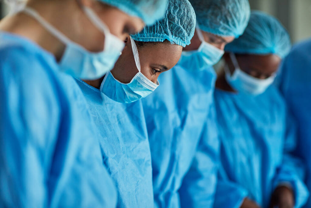 Сосредоточен на операционной. Обрезанный снимок группы хирургов, выполняющих медицинскую процедуру в операционной. - Фото, изображение