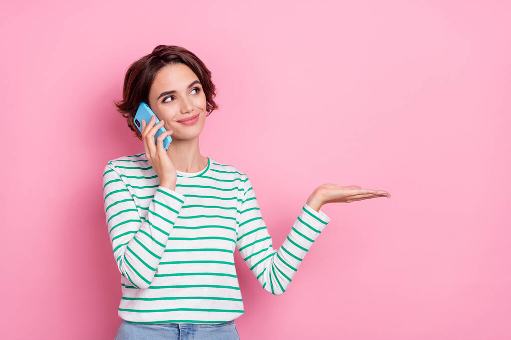 Portret van aantrekkelijke vrolijke meisje houden op palm kopie lege ruimte bieden praten op telefoon geïsoleerd over roze pastel kleur achtergrond - Foto, afbeelding