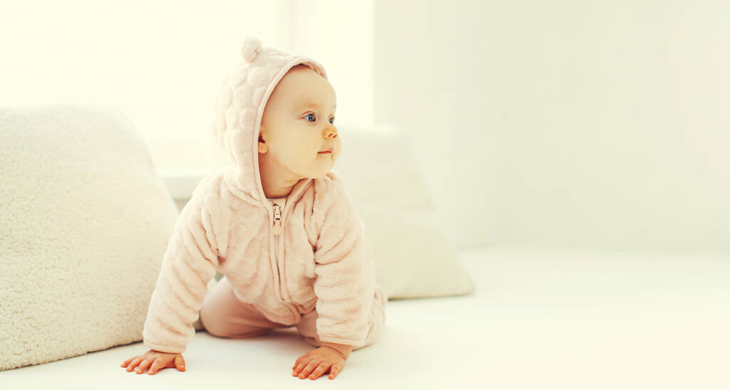 Portrait de mignon petit bébé en peignoir en chambre blanche à la maison près de la fenêtre - Photo, image
