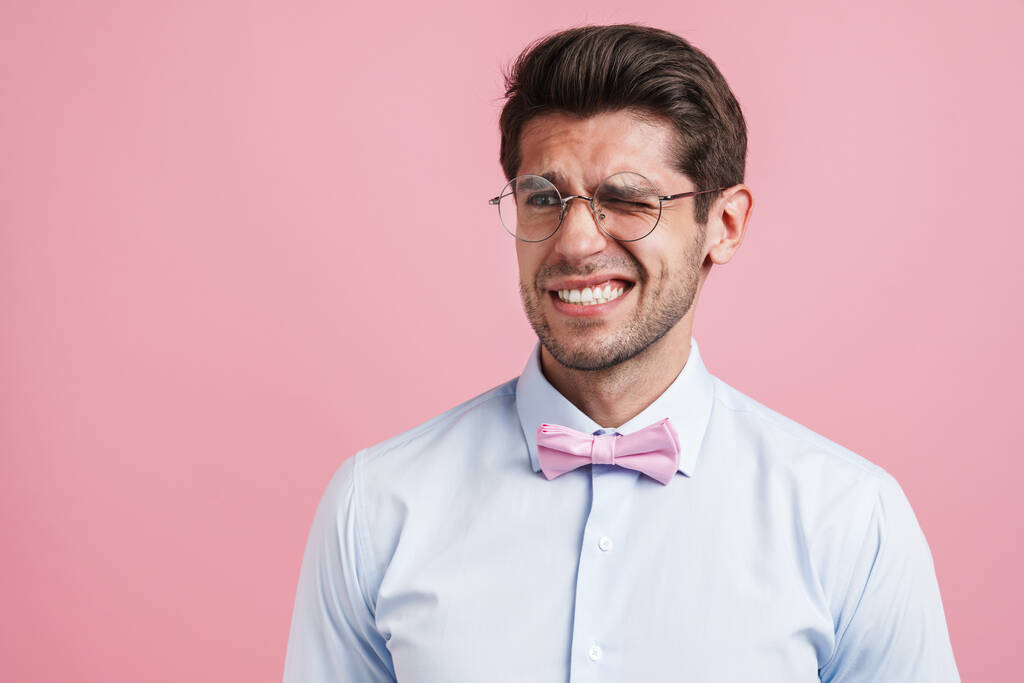 Молодий білий чоловік носить краватку з бантом і виглядає ізольовано на рожевому фоні
 - Фото, зображення