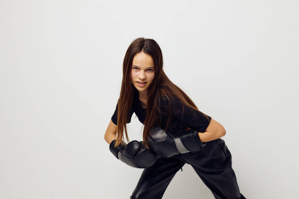 jeune belle femme en noir sport uniforme gants de boxe posant fond isolé - Photo, image