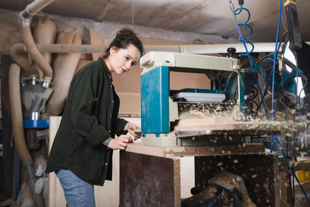 Junger Schreiner arbeitet in Werkstatt mit Dickenhobel  - Foto, Bild