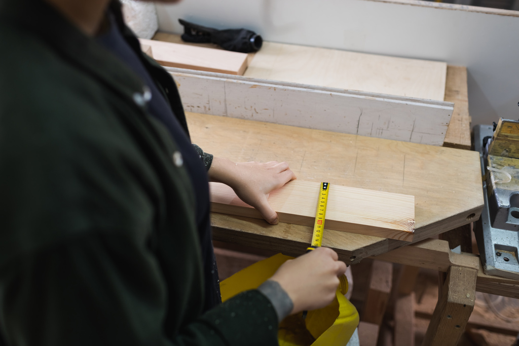 Gekropte weergave van meubelontwerper meten houten plank in werkplaats  - Foto, afbeelding