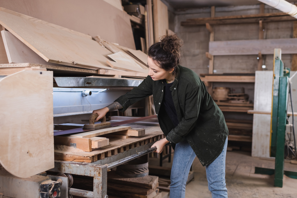 Jonge timmerman polijsten houten plaat in werkplaats  - Foto, afbeelding