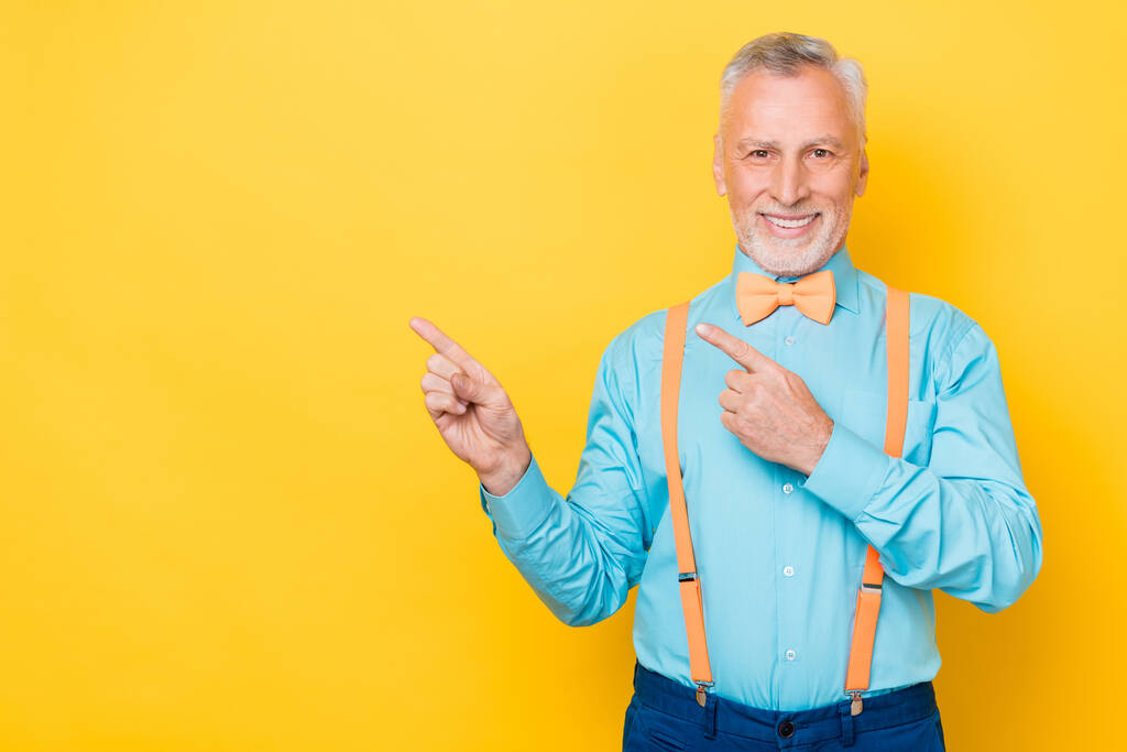 Photo of elder white hairdo man index promo wear teal shirt suspenders bow tie isolated on yellow color background - Photo, Image