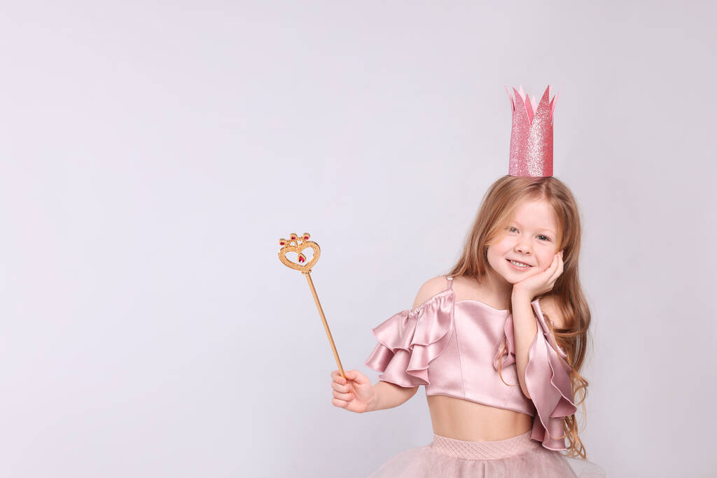Roztomilá dívka v pohádkových šatech s růžovou korunou a kouzelnou hůlkou na světle šedém pozadí, prostor pro text. Malá princezna - Fotografie, Obrázek
