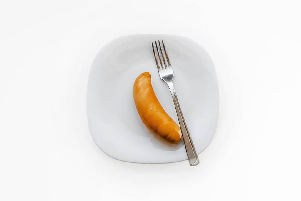白い皿の上に横たわる鶏のソーセージと金属フォーク - 写真・画像