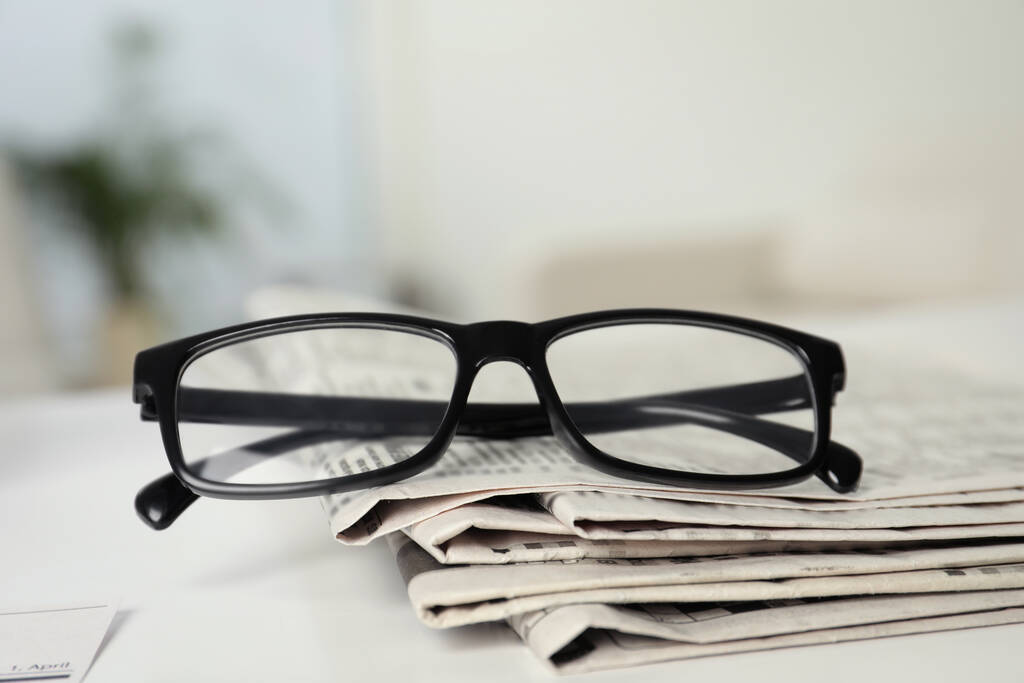 Stack of newspapers and glasses on white table indoors - Photo, Image