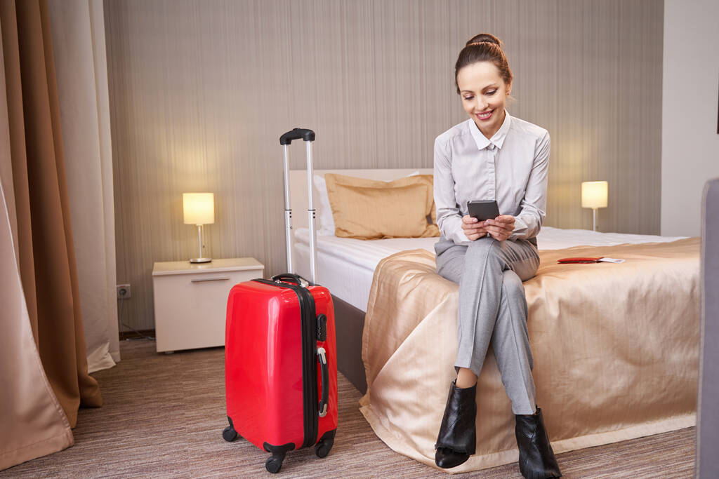 Vreugdevolle toerist die sms 'jes leest in haar hotelkamer - Foto, afbeelding