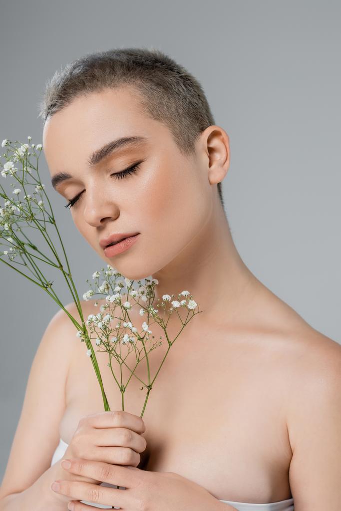 sensual woman with closed eyes near branches of white gypsophila isolated on grey - Photo, Image