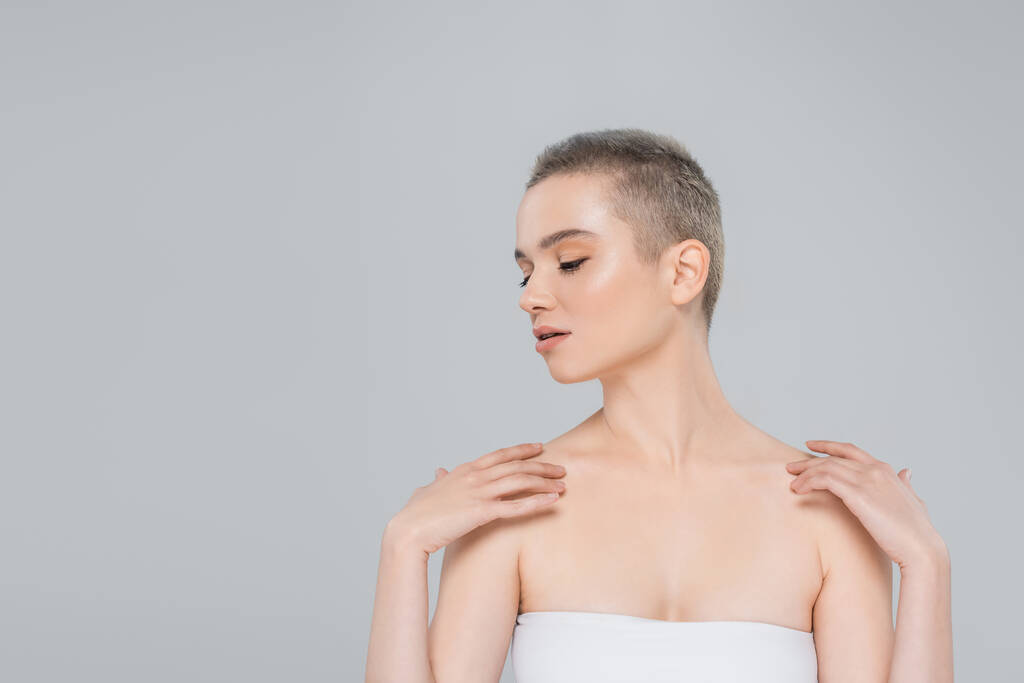 young woman with closed eyes touching bare shoulders isolated on grey - Photo, Image