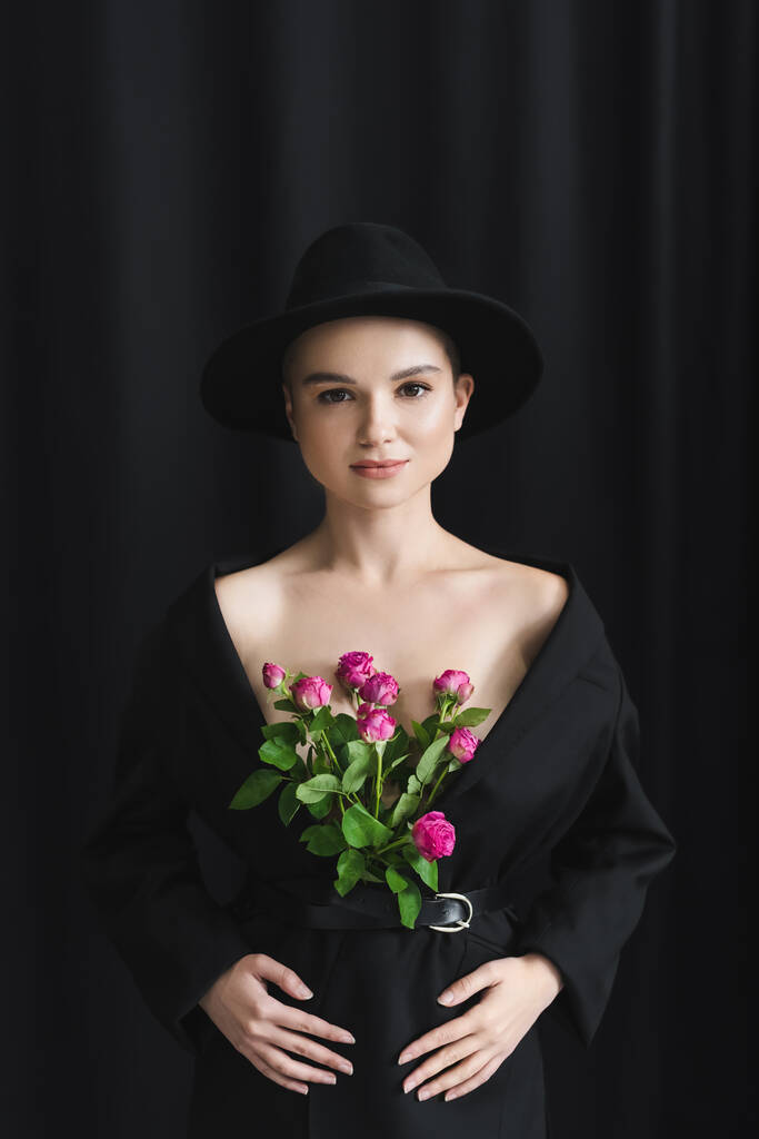 vista frontale di giovane donna con rose rosa in blazer nero su sfondo scuro - Foto, immagini