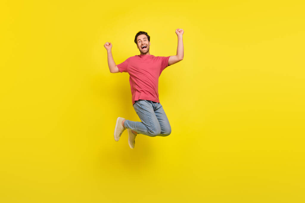 Ganzkörper-Foto von cool brunet millennial guy jump jell tragen T-Shirt Jeans Schuhe isoliert auf gelbem Hintergrund - Foto, Bild