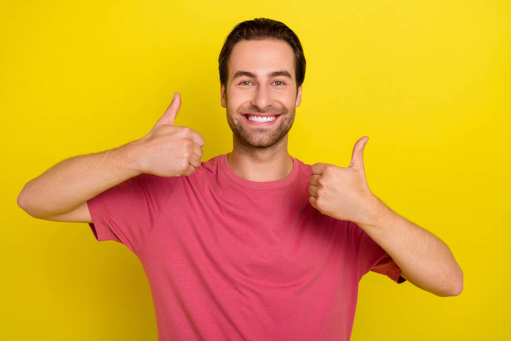 Zdjęcie miłego odpowiedzialnego faceta podnieść kciuk do góry zatwierdzić decyzję nosić różowy t-shirt odizolowany żółty kolor tła - Zdjęcie, obraz