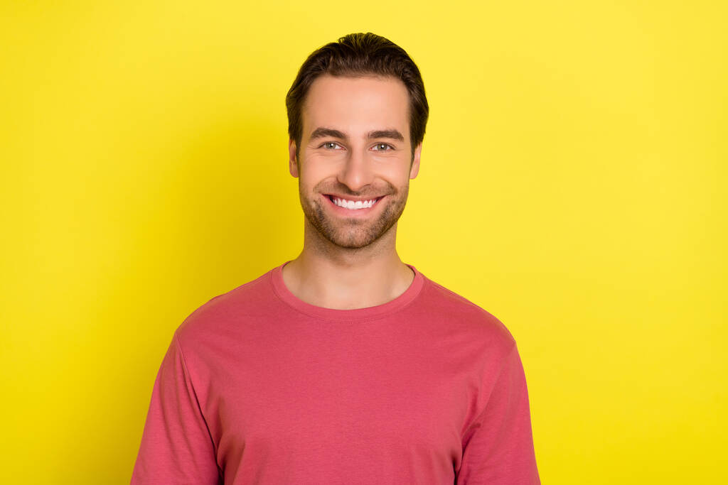 Фото позитивного красивого бородатого хлопця виглядає камера блискуча посмішка носить рожеву футболку ізольований жовтий кольоровий фон
 - Фото, зображення
