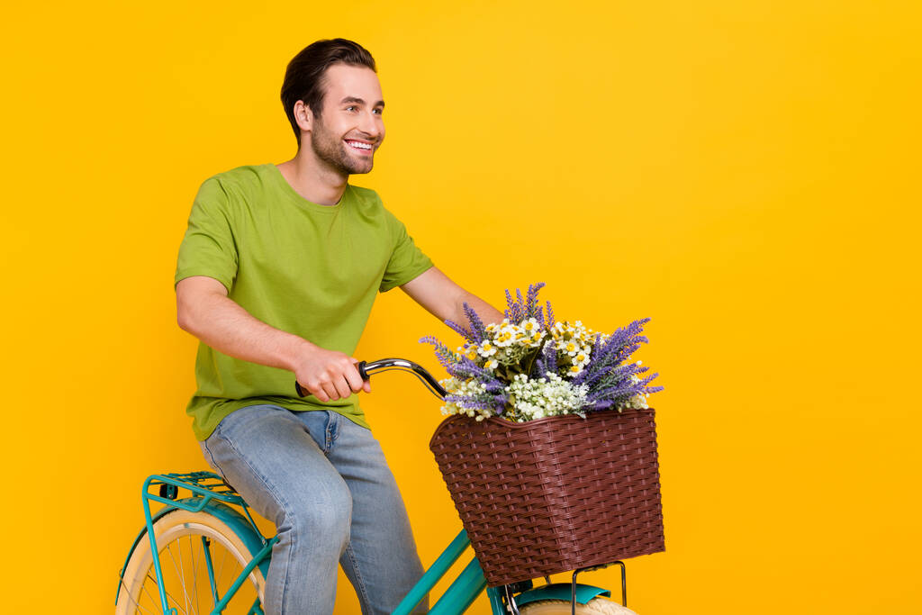 Фото оптимистичного брюнетка прическа молодой парень на велосипеде носить футболки джинсы изолированы на желтом фоне - Фото, изображение