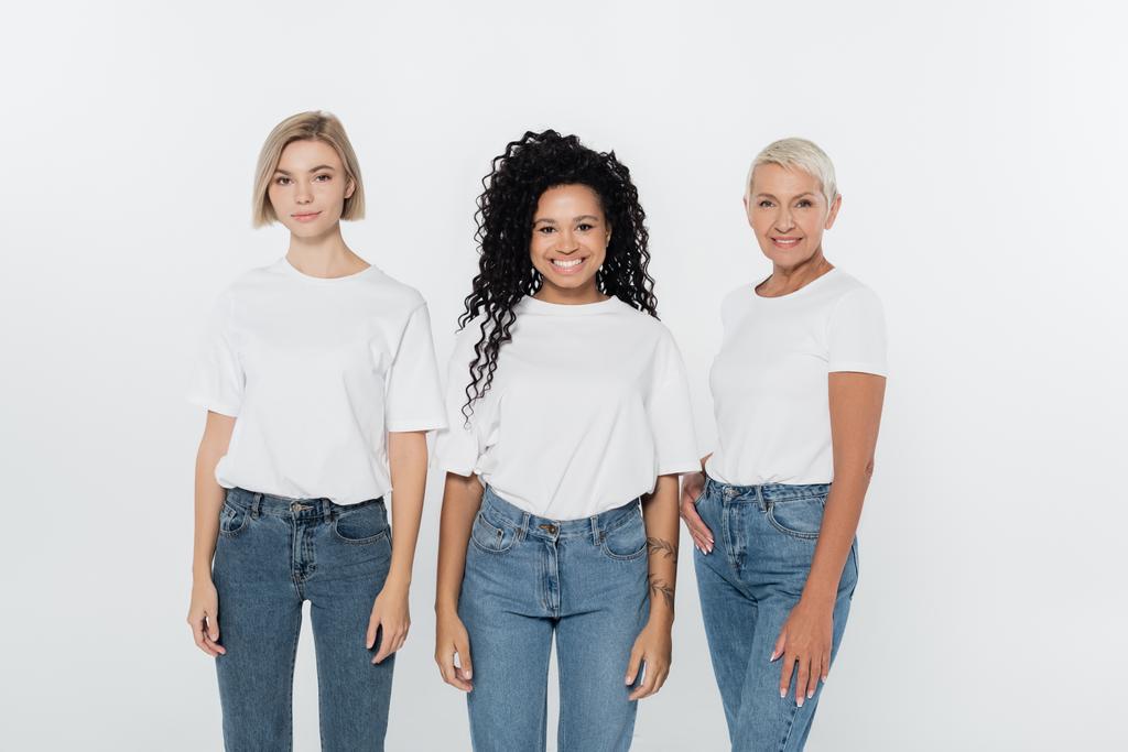 Счастливая африканская американка в белой футболке, стоящая рядом с друзьями, изолированными на серой  - Фото, изображение