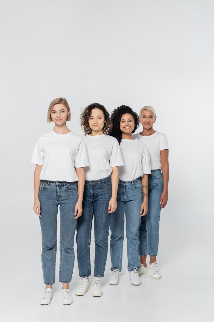Plná délka různých žen v džínách a tričkách na šedém pozadí, feminismus koncept - Fotografie, Obrázek