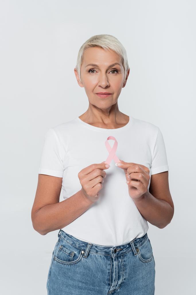 乳癌意識のリボンを持っている高齢女性は灰色で隔離されました  - 写真・画像