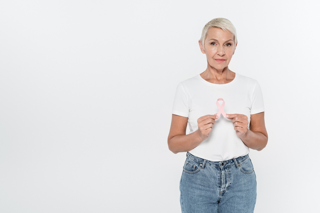 Elderly woman holding ribbon of breast cancer awareness isolated on grey  - Photo, Image