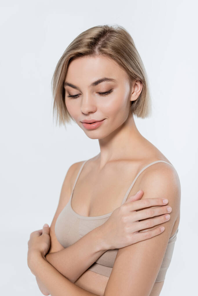 Young blonde woman touching shoulder isolated on grey  - Photo, Image