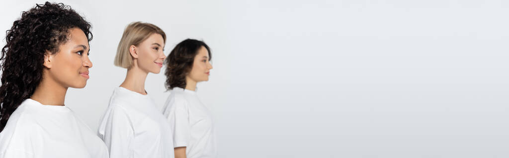 Positive african american woman standing near blurred friends isolated on grey, banner  - Photo, Image