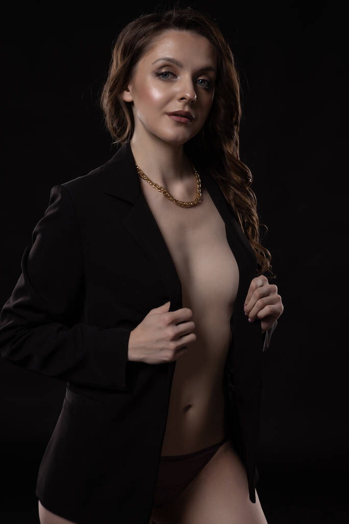 Ritratto di una donna d'affari sexy a figura intera in posa su uno sfondo nero in topless in una giacca che copre i suoi seni - Foto, immagini