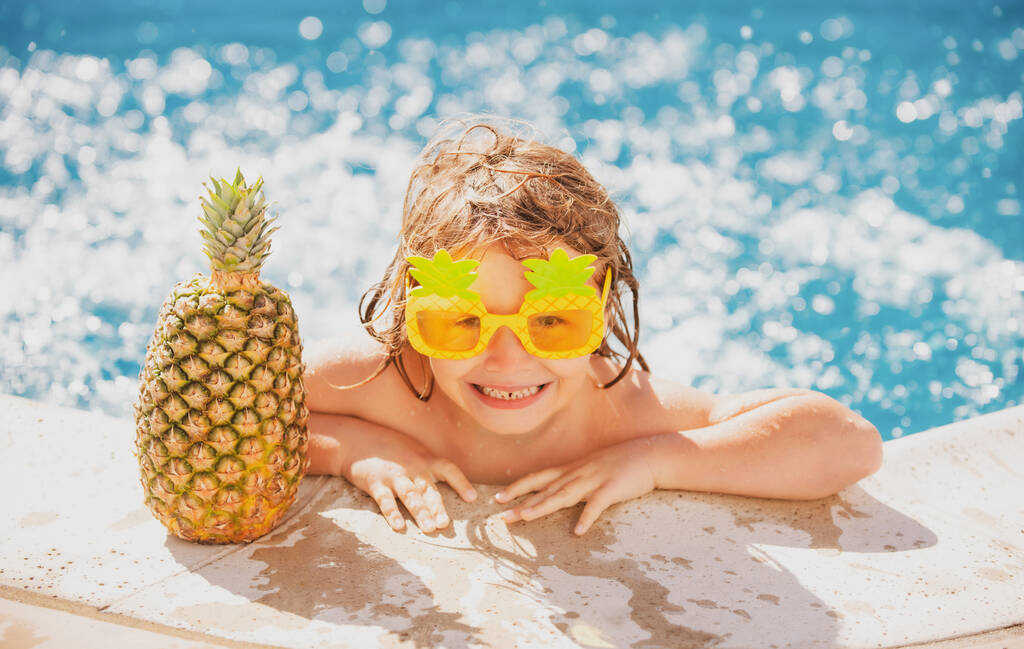 Boy child happy swimming in a pool. Little kid having fun in swim pool. Summer pineapple fruit. - Photo, Image