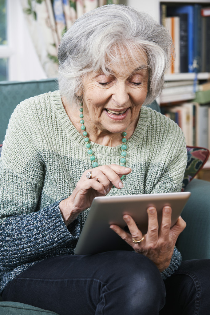 Oudere vrouw die thuis digitale tablet gebruikt - Foto, afbeelding