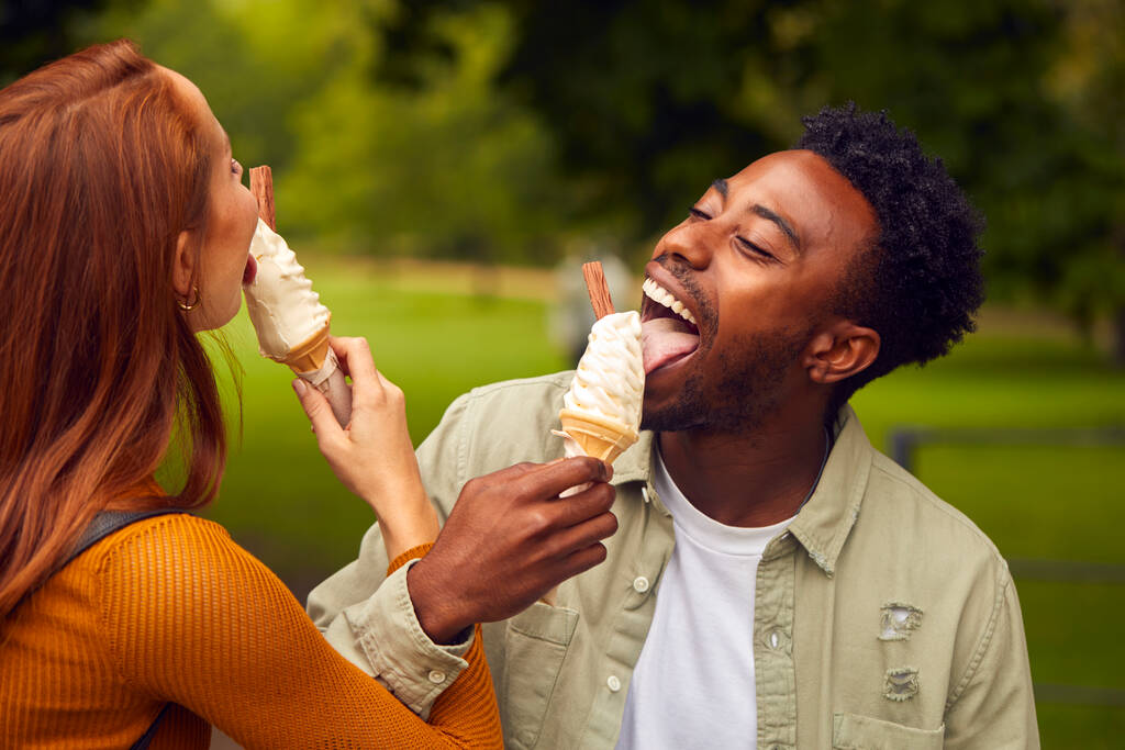 Młoda para podróżująca po mieście razem jedząca lody w parku - Zdjęcie, obraz
