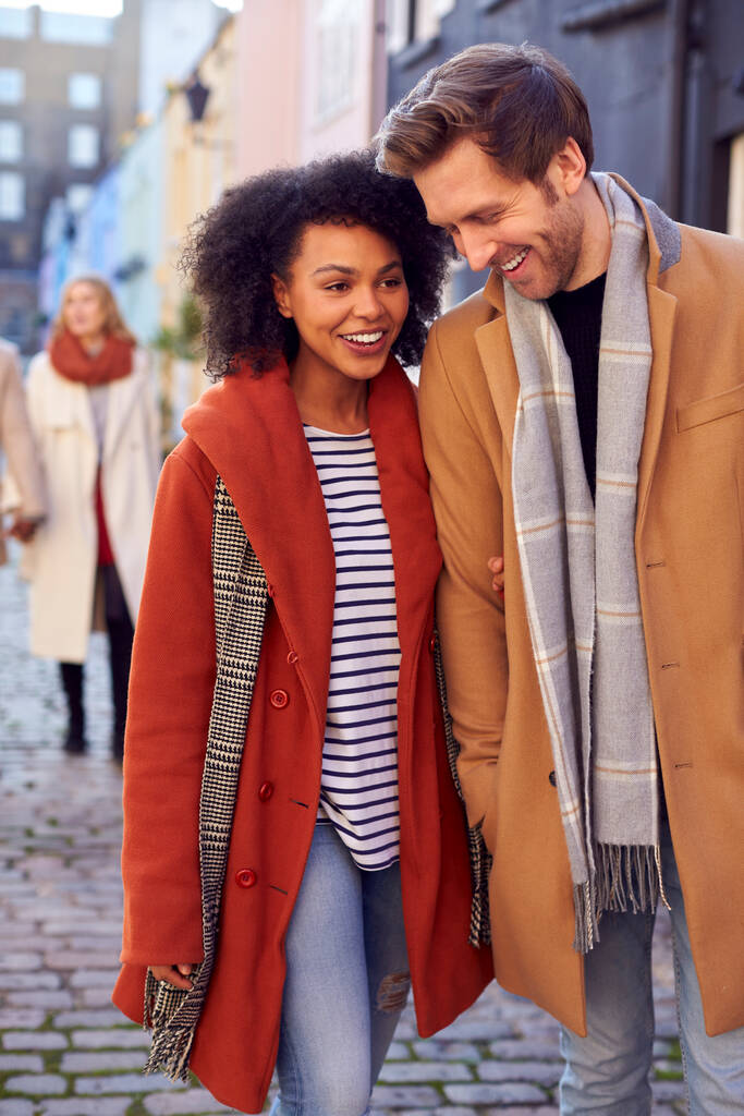 Мультикультурная пара с друзьями, прогуливающимися по улицам города осенью или зимой - Фото, изображение