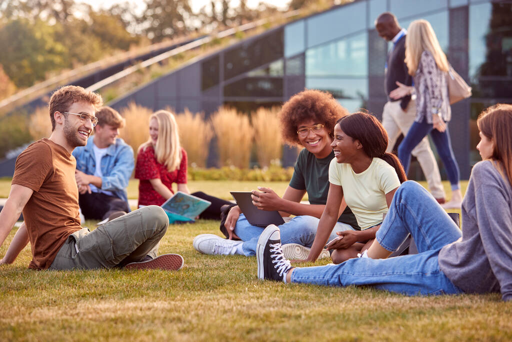 大学や大学生のグループは、キャンパスの外で草の上に座って話すと作業 - 写真・画像