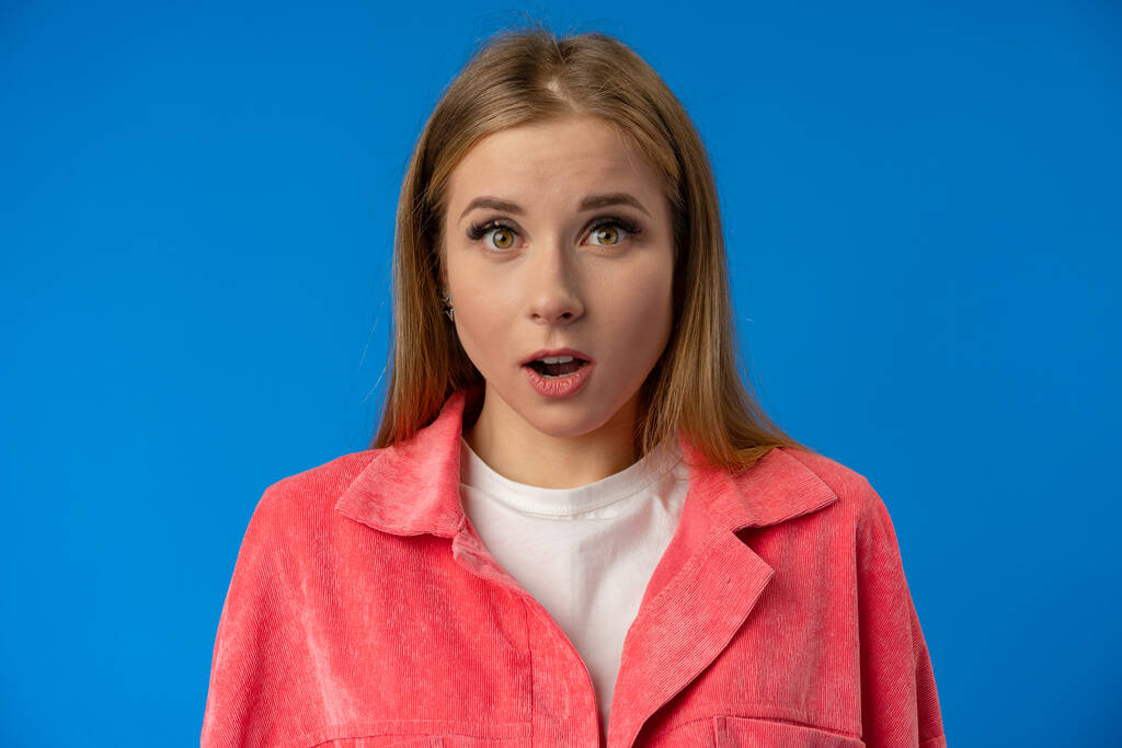 Negative nervous young woman in trouble over blue background - Photo, Image