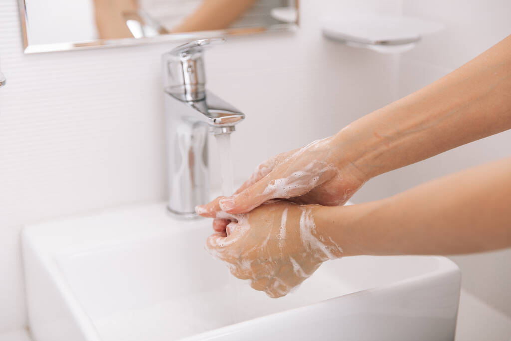 Akan su musluğunun altında ellerini yıkamak. Hijyen konsepti el detayı. Corona virüsünün önlenmesi için sabunla ellerini ovuşturmak, korona virüsünü halka yaymayı durdurmak için hijyen. Ya da umumi tuvalette. - Fotoğraf, Görsel