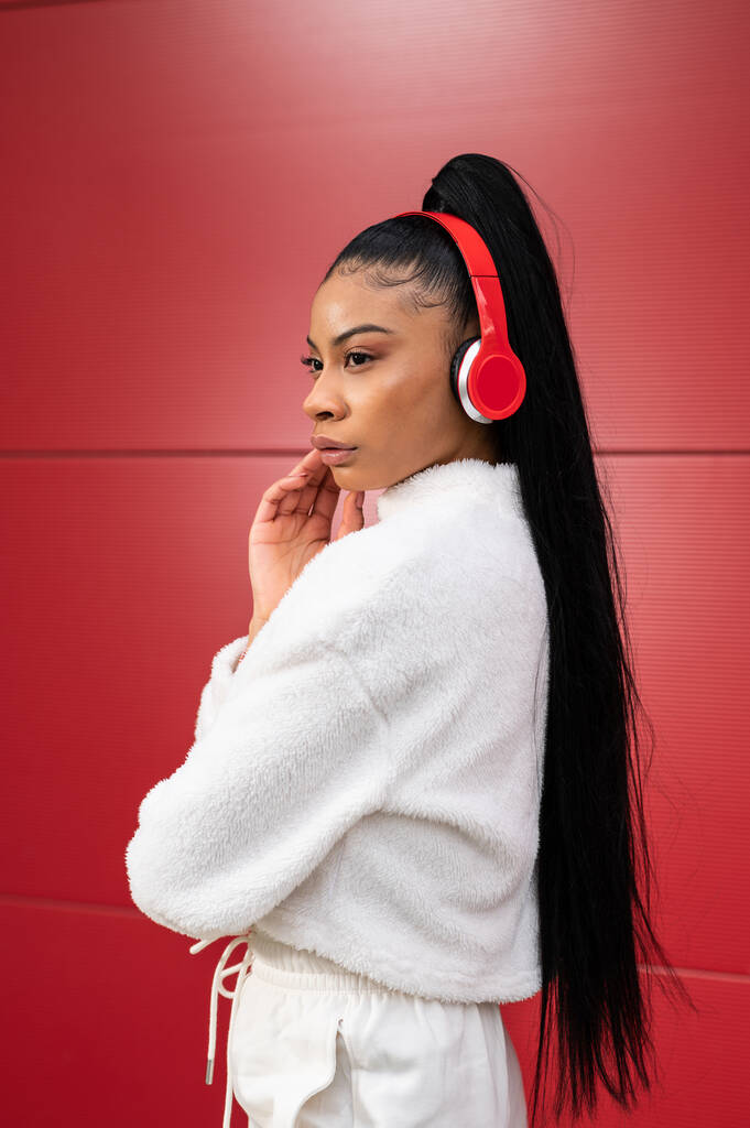 junge schöne Frau mit Kopfhörer hört Musik auf rotem Hintergrund - Foto, Bild