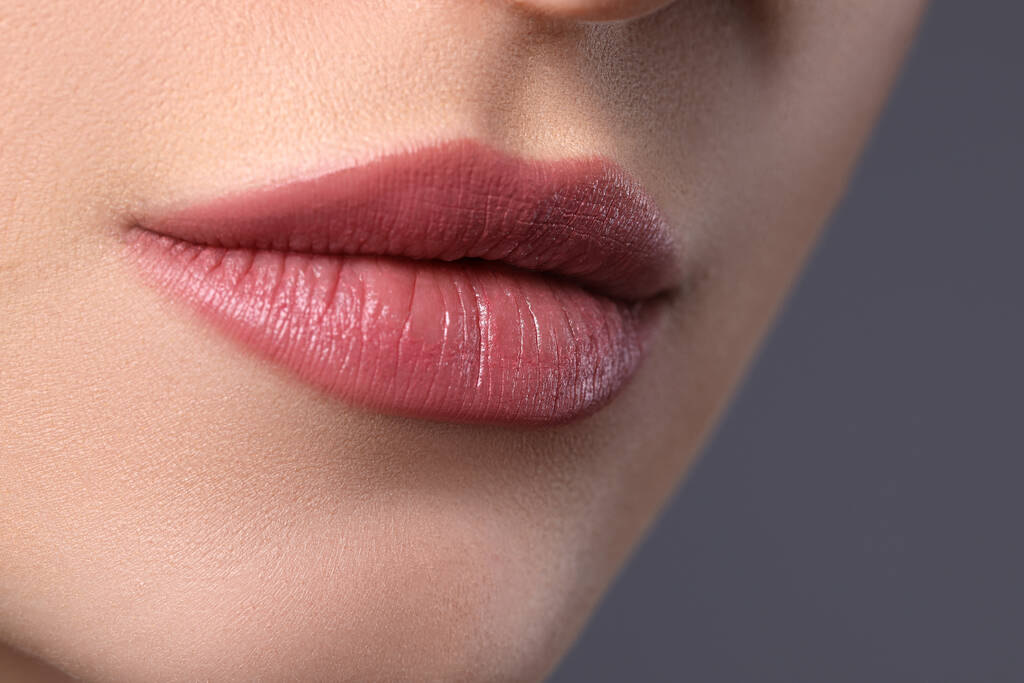 Vrouw met mooie lippen op grijze achtergrond, close-up - Foto, afbeelding