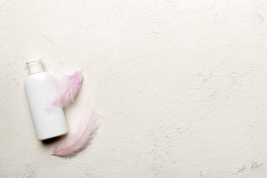 Set huidverzorgingsserums op roze pastelachtergrond met struisvogelveren. Spa cosmetisch product, crème pot, branding mock up, bovenaanzicht met kopieerruimte. - Foto, afbeelding