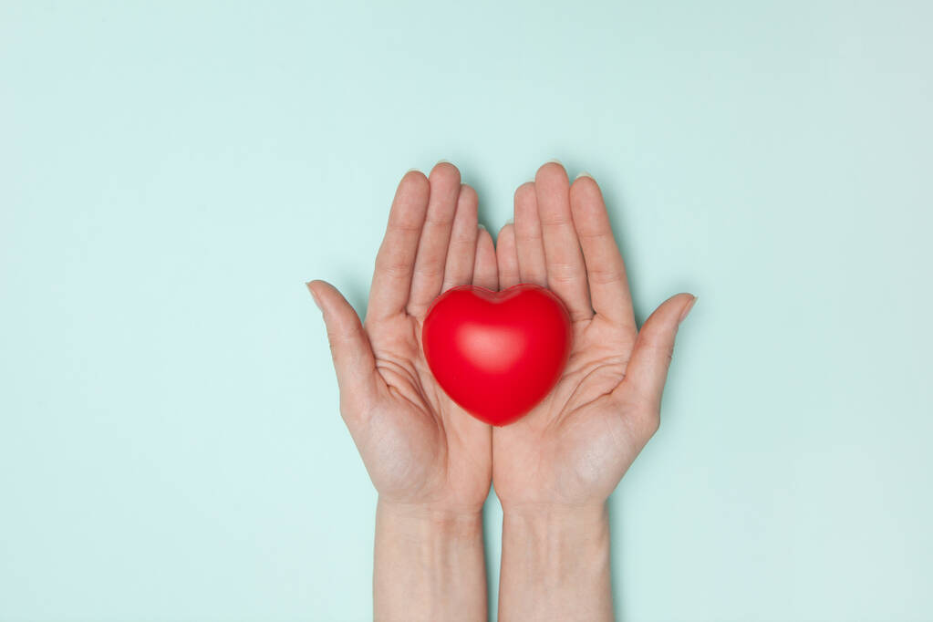 Υγεία, ιατρική και φιλανθρωπία έννοια - κοντά σε γυναικεία χέρια με μικρή κόκκινη καρδιά. Επίπεδη. - Φωτογραφία, εικόνα