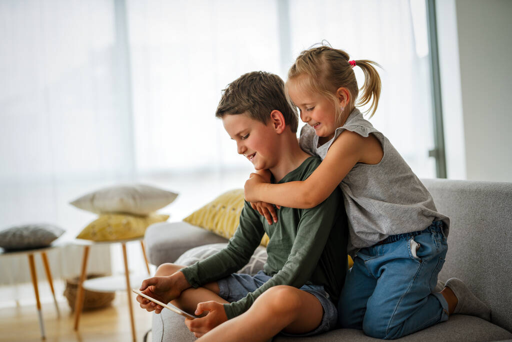 Petite fille et garçon regardant des vidéos ou jouant à des jeux sur leur tablette d'appareil numérique, smartphone. Concept de dépendance numérique des enfants. - Photo, image