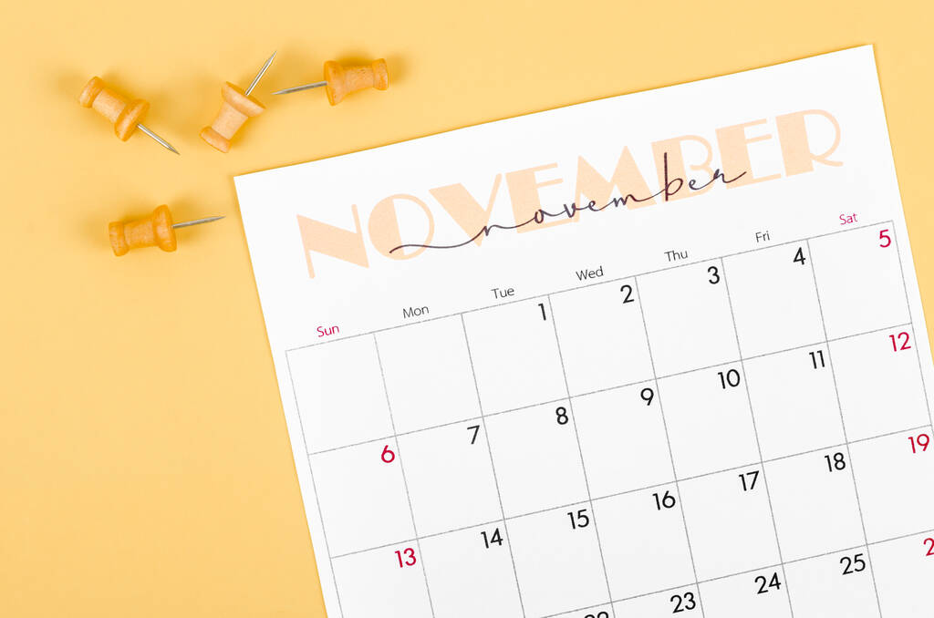 El calendario de noviembre de 2022 y el alfiler de madera sobre fondo amarillo. - Foto, imagen