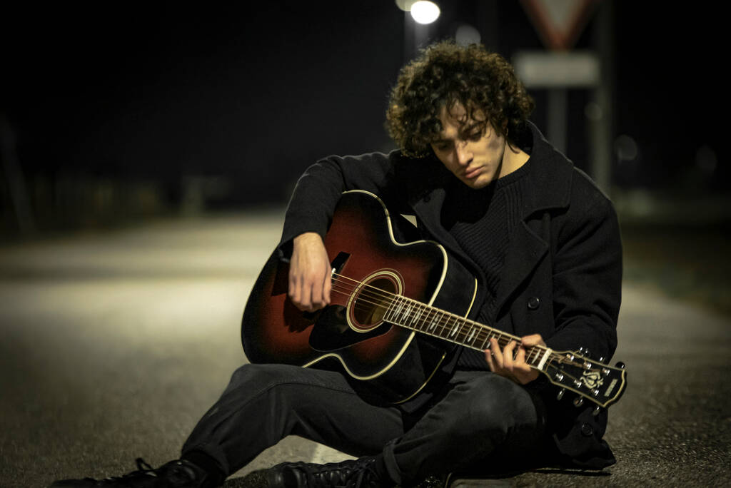 Muzyk z gitarą akustyczną sam na chodniku w nocy - Zdjęcie, obraz